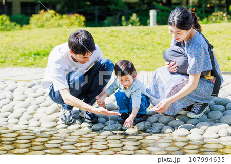 小川で水遊びをする家族 107994635