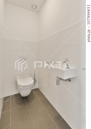 a bathroom with white walls and tile flooring the toilet is on the left side of the wall to the right 107994651