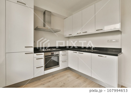 a kitchen with white cupboards and black counter tops on the wall, in an apartment development in south london 107994653
