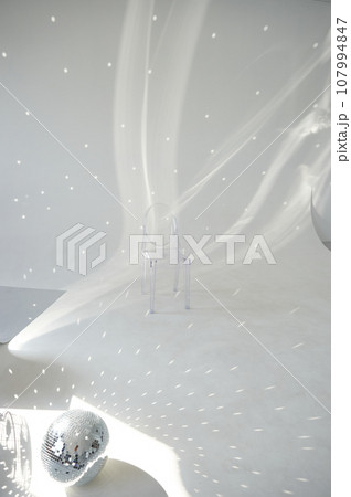 Bright room, futurism. Disco ball and glare on the wall. Transparent chair. Minimalism Bright room, futurism. Disco ball and glare on the wall. Transparent chair. Minimalism 107994847