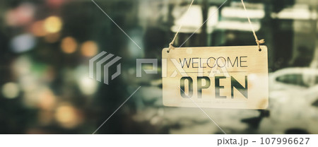 Open sign broad hanging on wood door front of cafe. Welcome. Open. open sign board on glass door in modern cafe coffee shop ready to service. Open sign broad hanging on wood door front of cafe. Welcome. Open. open sign board on glass door in modern cafe coffee shop ready to service. 107996627