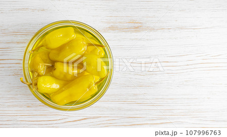 Pickled yellow greek pepper, pepperoncini or friggitelli in bowl on white wooden background Pickled yellow greek pepper, pepperoncini or friggitelli in bowl on white wooden background 107996763