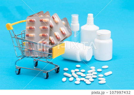 Pills and Capsules in Shopping Cart on Blue Background Pills and Capsules in Shopping Cart on Blue Background 107997432