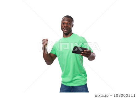 A 30-year-old American man dressed in a light green basic T-shirt rejoices while watching a video on A 30-year-old American man dressed in a light green basic T-shirt rejoices while watching a video on 108000311