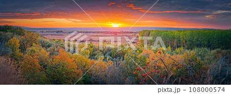 Autumn evening over the valley. Beautiful fall panorama with the multicolored forest and orange october sunset 108000574