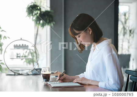 手帳にスケジュールを書き込むビジネスウーマン 手帳にスケジュールを書き込むビジネスウーマン 108000765