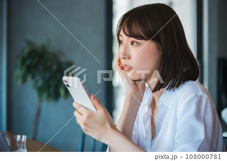 スマートフォンを見て考える若いビジネスウーマン スマートフォンを見て考える若いビジネスウーマン 108000781