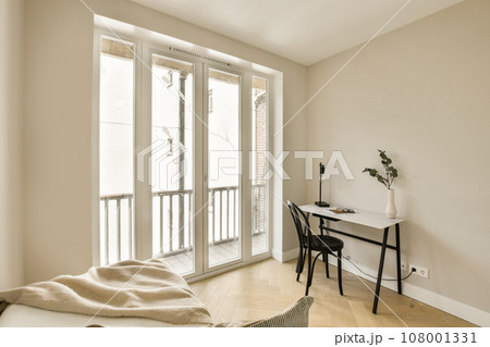 a room with a desk, chair and sliding glass door that leads to a balcony area in the apartment building 108001331