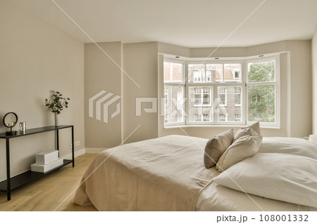 a bedroom with white walls and wood flooring in front of a large window that looks out onto the street 108001332