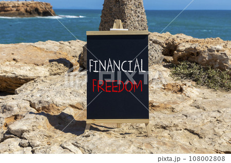 Financial freedom symbol. Concept words Financial freedom on beautiful black chalk blackboard. Chalkboard. Beautiful stone sea sky background. Business financial freedom concept. Copy space. 108002808