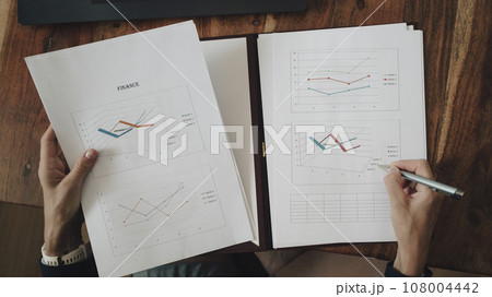 Businesswoman reviewing and reading financial report paperwork with data 108004442