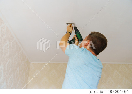 A man is working on the installation of a ceiling luminaire on the ceiling. 108004464