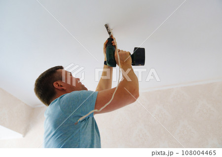 A man is working on the installation of a ceiling luminaire on the ceiling. 108004465
