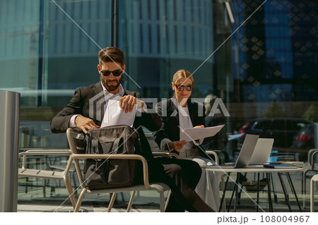 Two business partners working with documents sitting outside of office on cafe terrace 108004967