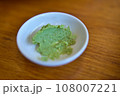The Green wasabi sauce or paste in bowl, with chopsticks or spoon over plain colourful background. selective focus 108007221