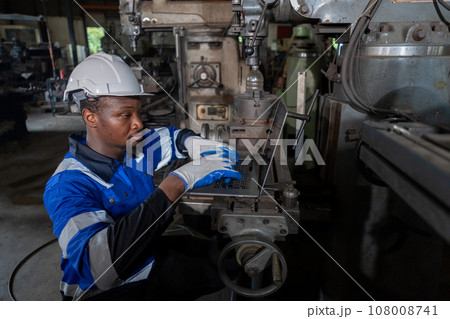 Male African American workers wearing uniform safety and hardhat using laptop working at machine 108008741