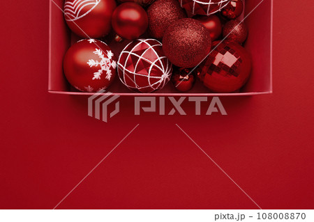 Red Christmas baubles decoration in the box on red background Red Christmas baubles decoration in the box on red background 108008870