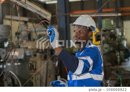 Male African American workers wearing uniform safety and hardhat working an iron cutting machine Male African American workers wearing uniform safety and hardhat working an iron cutting machine 108008922