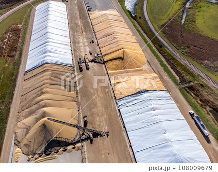 Drone view over grain storage piles being filled and covered 108009679