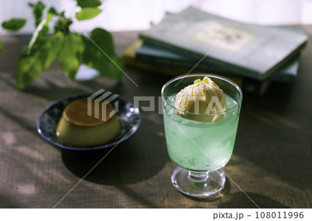 夕方の窓辺に置かれたクリームソーダとプリン 108011996