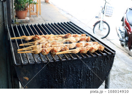 Raw wings grilling on black stove. 108014910