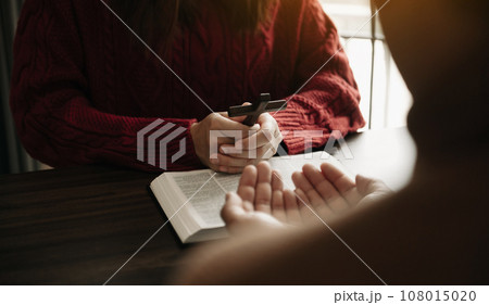 Two people reading and study bible in home and pray together.Studying the Word Of God With Friends. in sun light. 108015020