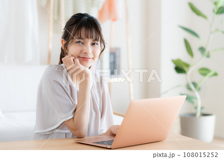 リビングでパソコンを使う若い女性 108015252