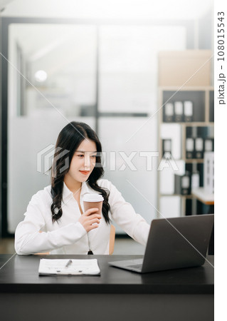 Successful Asian Businesswoman Analyzing Finance on Tablet and Laptop at Office Desk tax, report, accounting, statistics, and analytical research concept. 108015543