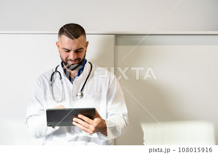 Online medicine with handsome man doctor with tablet computer having consultation online looking in device screen. 108015916