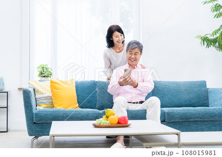 リビングでスマホを持つシニア夫婦 リビングでスマホを持つシニア夫婦 108015981