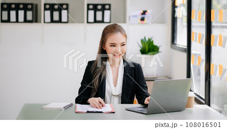 Successful Asian Businesswoman Analyzing Finance on Tablet and Laptop at Office Desk tax, report, accounting, statistics, and analytical research concept. 108016501