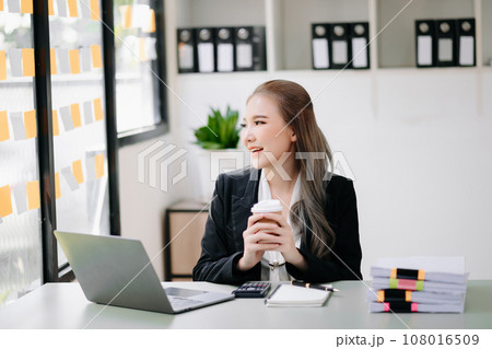 Successful Asian Businesswoman Analyzing Finance on Tablet and Laptop at Office Desk tax, report, accounting, statistics, and analytical research concept. 108016509