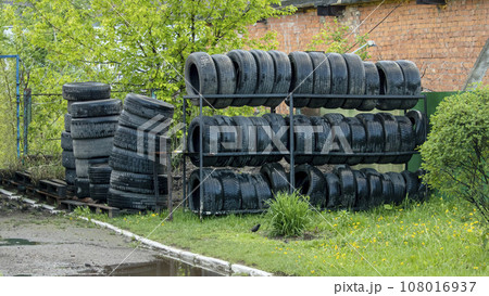 old and wet car tires on a shelf near a car service old and wet car tires on a shelf near a car service 108016937