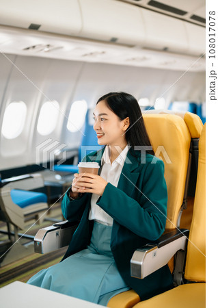 Young Asian executive excels in first class, multitasking with digital tablet, laptop and smartphone. Travel in style, work with grace. in morning light. 108017078
