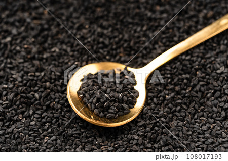 Black cumin seeds on golden spoon macro photography Black cumin seeds on golden spoon macro photography 108017193