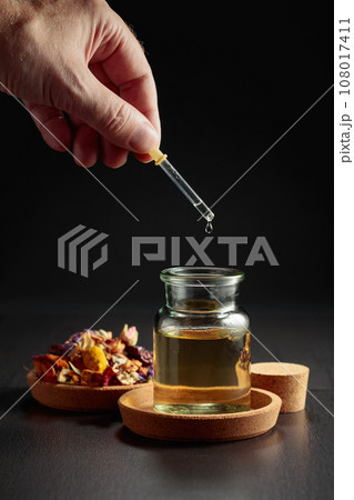 Dropping essential oil or herbal tincture into a small bottle. Dropping essential oil or herbal tincture into a small bottle. 108017411