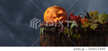 Carved Halloween pumpkin with burning candle on a background of cloudy sky. Carved Halloween pumpkin with burning candle on a background of cloudy sky. 108017440