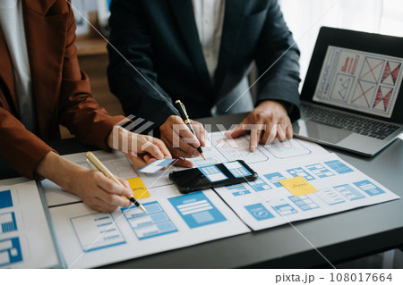 UX developer and ui designer brainstorming about mobile app interface wireframe design with customer breif and color code at office.. UX developer and ui designer brainstorming about mobile app interface wireframe design with customer breif and color code at office.. 108017664
