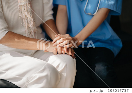 Close up view of old woman leaning on nurse while siting. 108017757