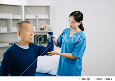 Physiotherapist Helping Patient While Stretching His Leg in bed in clinic . Physiotherapist Helping Patient While Stretching His Leg in bed in clinic . 108017863