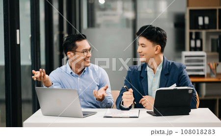 Two Asian business workers talking on the smartphone, tablet and using laptop at the office. 108018283