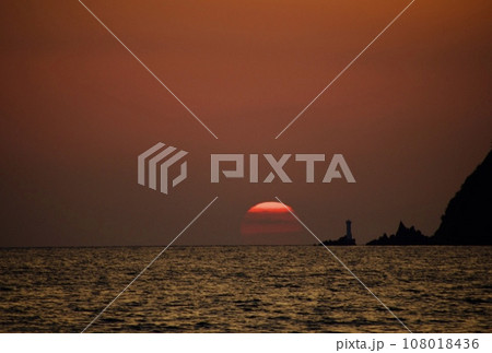秋の海の水平線に沈みかけた夕日8 108018436