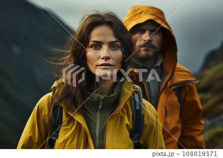 Portrait of happy couple in touristic outwear near the tent camp against the backdrop of picturesque mountain landscape. Caucasian family is engaged in a mountain hiking. Tourism and active lifestyle. 108019371