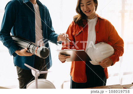 Engineer desk with object paper and tablet with blurry engineer teamwork hardworking to consults about their building project.. Engineer desk with object paper and tablet with blurry engineer teamwork hardworking to consults about their building project.. 108019758