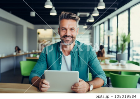 Cheerful Caucasian middle-aged man in casual clothes holding a tablet sits at table in cafe. Happy smiling mature businessman, successful entrepreneur or employee works online. Remote work concept. Cheerful Caucasian middle-aged man in casual clothes holding a tablet sits at table in cafe. Happy smiling mature businessman, successful entrepreneur or employee works online. Remote work concept. 108019884