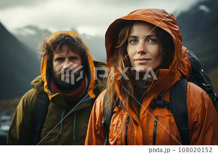 Portrait of happy couple in touristic outwear near the tent camp against the backdrop of picturesque mountain landscape. Caucasian family is engaged in a mountain hiking. Tourism and active lifestyle. 108020152