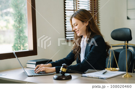 Feale judge in a courtroom the gavel, working with smart phone and laptop and digital tablet computer on wood table Feale judge in a courtroom the gavel, working with smart phone and laptop and digital tablet computer on wood table 108020460