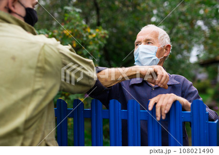 Senior man in mask having conversation with his neighbour Senior man in mask having conversation with his neighbour 108021490