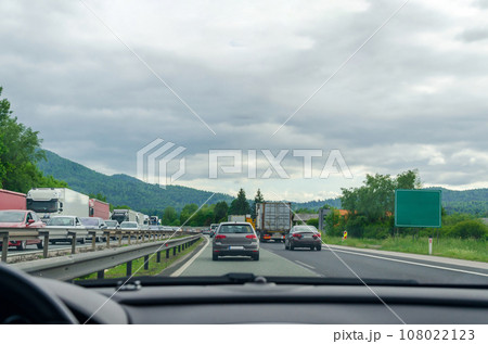 Driving on a highway through a picturesque landscape in - view from a car windshield Driving on a highway through a picturesque landscape in - view from a car windshield 108022123