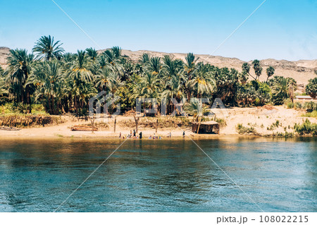 Friendly Locals Waving from Nile Shore to Cruise Ship. Egypt Summer Travel 108022215
